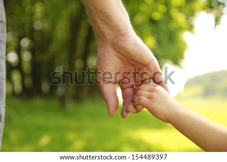 A Parent Holds The Hand Of A Small Child
