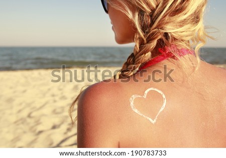 a heart of the cream on the female back on the beach