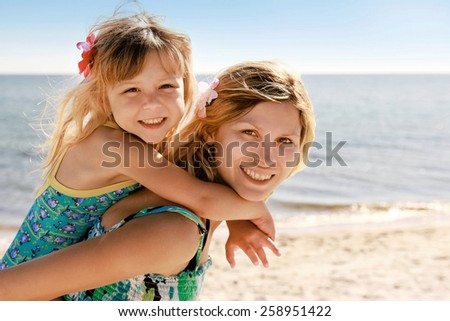 Mama and her little daughter playing on the beach
