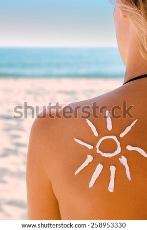 of sun cream on the female back on the beach