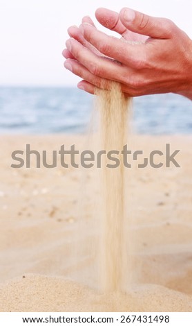 a male hand pours sand on the seashore