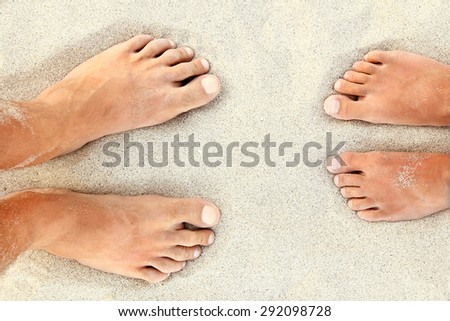 Man and girl feet in the sand near the sea