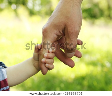 a the parent holding the hand of a small child