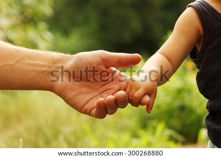 a the parent holding the hand of a small child