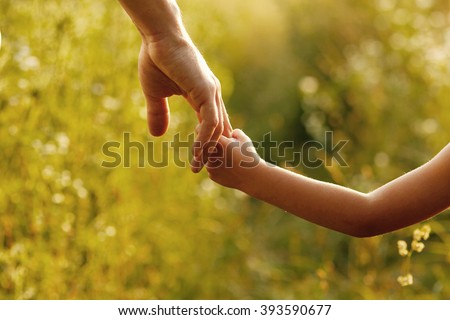 a the parent holds the hand of a small child