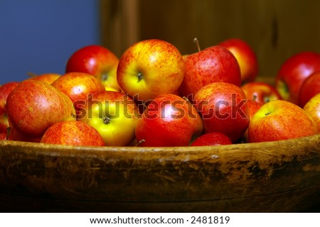 A wooden bowl filled with red apples; shallow depth of field with focus on apples in the center