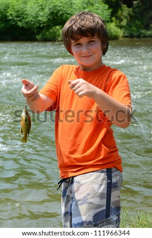 Young boy smiling about catching a fish from the river