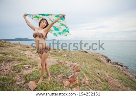 Portrait of sexy young asian woman with blowing fabric on mountain and sea