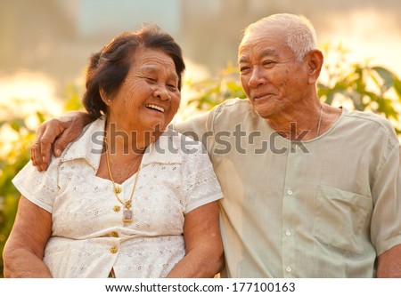 Happy Asian Senior Couple Sitting Outdoors On Sunset