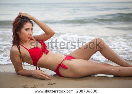 Beautiful asian woman in red bikini posing at beach