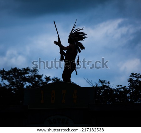 Silhouette of American Indian warrior man with feather headdress and tomahawk