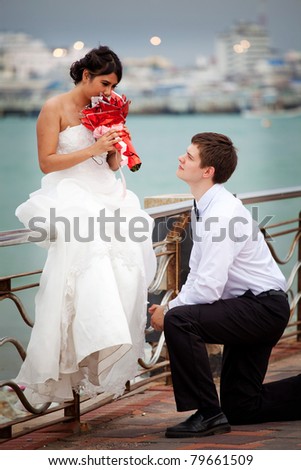 Newly married knee gives the flower beside the sea
