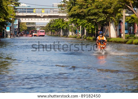 BANGKOK, THAILAND - NOVEMBER 12 : Two men on a motorbike navigating through the flood after the heaviest monsoon rain in 20 years in the capital on November 12,2011 Bangkok, Thailand.