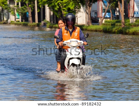 BANGKOK, THAILAND - NOVEMBER 12 : Two people on a motorbike navigating through the flood after the heaviest monsoon rain in 20 years in the capital on November 12,2011 Bangkok, Thailand.