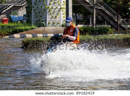 BANGKOK, THAILAND - NOVEMBER 12 : A man on a motorbike navigating through the flood after the heaviest monsoon rain in 20 years in the capital on November 12,2011 Bangkok, Thailand.