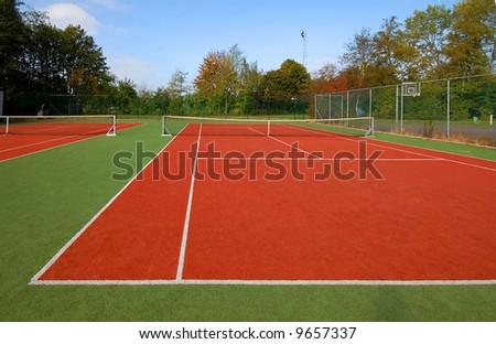 tennis court under blue sky, with autumn trees on the side.