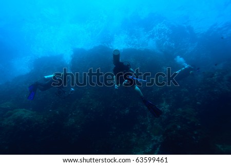 Diver swimming to sea surface with wave above