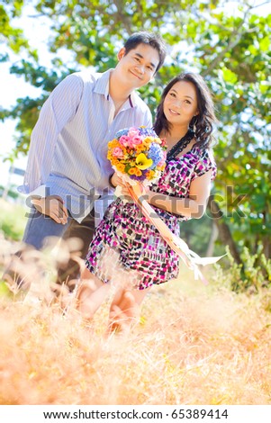 stock photo Pre wedding couple at meadow grass field with bouquet