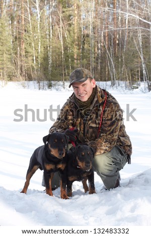 The man (Popov Dmitry) holds on a lead of two hunting dogs Jagdterriers in the winter, looks in the camera