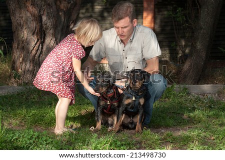 The father shows to the daughter as it is necessary to communicate with two sitting little dogs