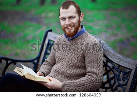 bearded guy reading a book in the park