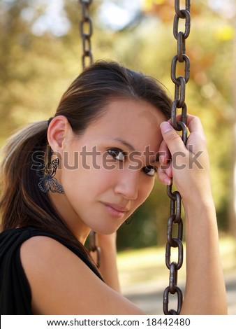 Young asian american woman sitting on swing with chains