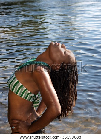 Black woman outdoors in water bending head up