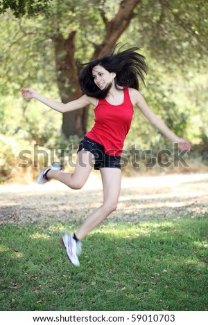 Young latina teen girl jumping outdoors motion blur