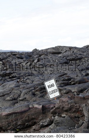 Black lava flow covering road with road closed sign