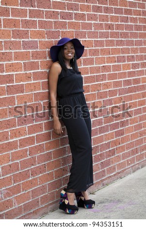 Young Black woman standing against red brick wall