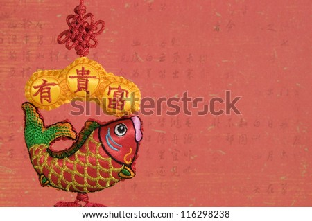 Chinese Hanging Fish Decoration on Old Red Chinese Calligraphy Background. Chinese New Year.