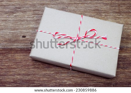 brown paper parcel tied with red and white string on wood table