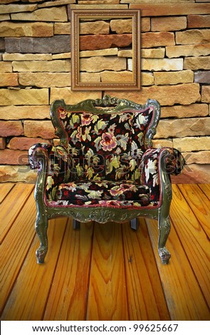 Antique armchair in the brick wall room with a frame hanging on.