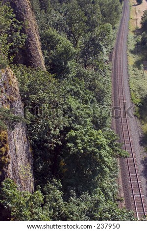 Railroad tracks running past cliff.