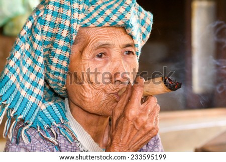 Minnanthu, Myanmar - 24 January 2010: Portrait of an old woman smoking a big cigar at the archaeological site of Bagan on Myanmar