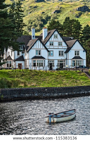 Houses and boat at the lakeside the of Loch Katrine, Stirling District, Scotland, United Kingdom