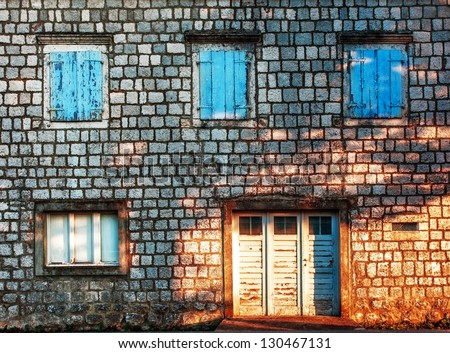 Old stones wall with door and windows in sunset light