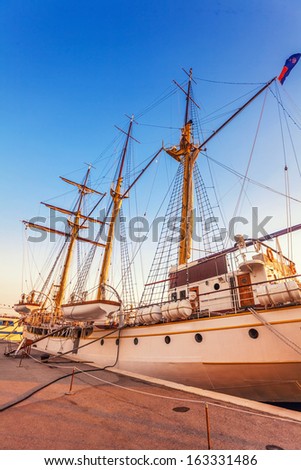 Old sailing ship in the rays of light of the setting sun in the port