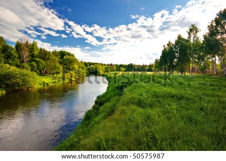Green field with river under blue sky
