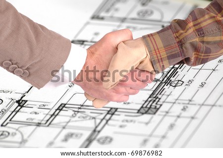 Worker and a businessman shaking hands over house renovation plans house renovation contract deal and plans
