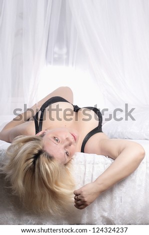 nice young woman full, in black linen, lies on  white round bed/Morning