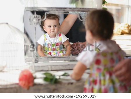 Two-year-old baby with mistrust considers the reflection in a mirror/About the mirror