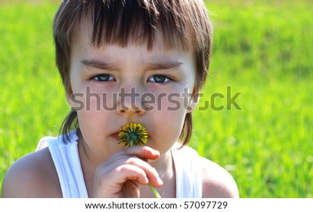 Serious boy with  dandelion in hands, against solar meadow. Concept of preservation of nature./Preserve nature