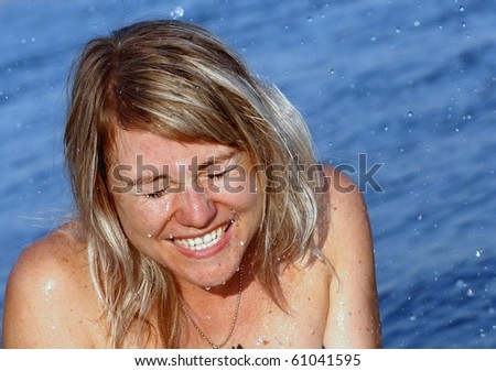 Girl close-up on the background of water. She laughs, her eyes shutting his eyes from the water splashes and drops. /Moments of happiness