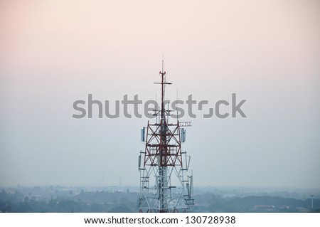 Communication tower with mobile antenna in twilight sky, Thailand.