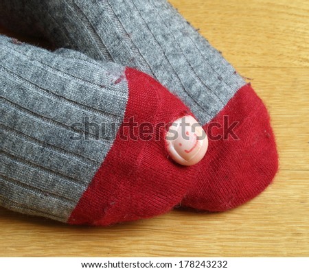 sock with a hole and a smiley painted on the toenail