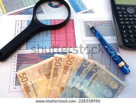 business and financial success concept: magnifier, calculator, bank notes, pen and documents