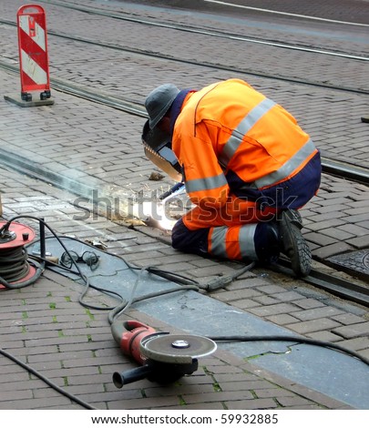 worker with protective mask and gloves welding train rail and sparks spreading