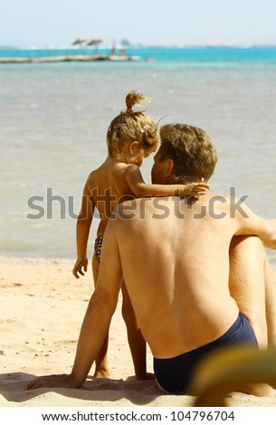 Back view of father and daughter looking to ocean