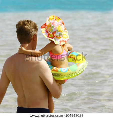 Daddy keeps little daughter on hands and going to swim in the ocean